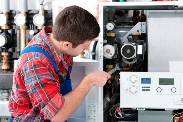 HVAC technician inspecting and repairing boiler controls in Ogden
