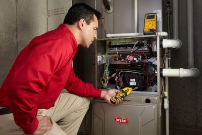 Heating and air conditioning technician servicing an indoor furnace in Ogden, UT